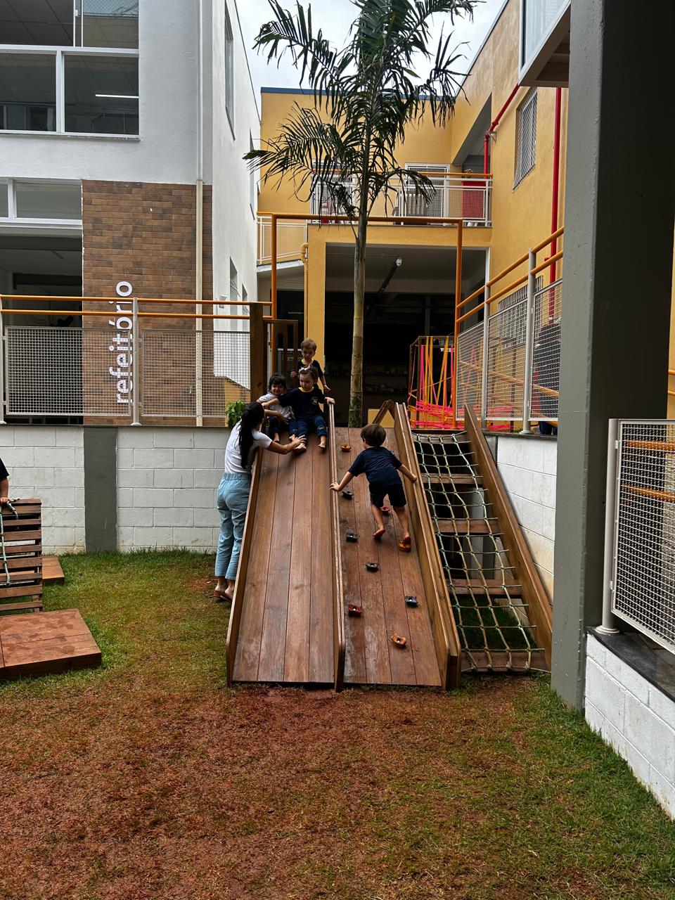 Circuito de madeira, rampa de escalada e escorregador no pátio da escola